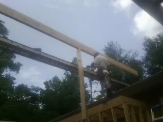 Carpenter setting a ridge beam over a new addition frame — Ice Dam Removal by Roofing Brothers in Huffman