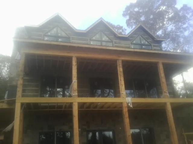 Dormers and porch framing on a large log home under construction — Roof Coating work by our crew in Huffman