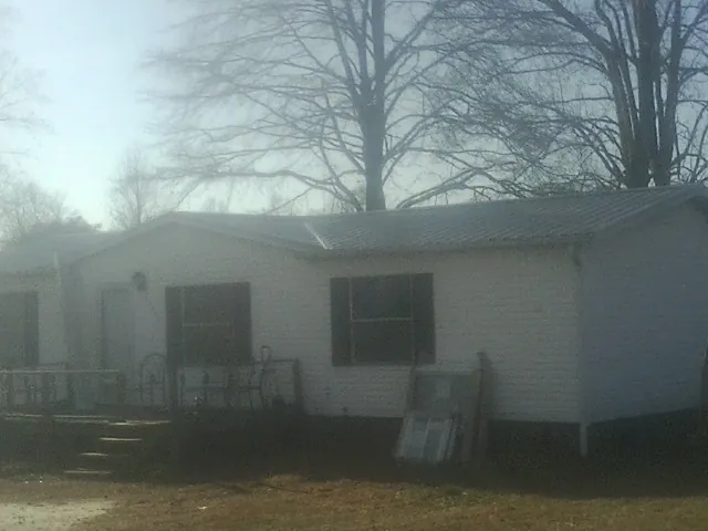 New metal roof on a white painted brick home on a foggy morning in Huffman