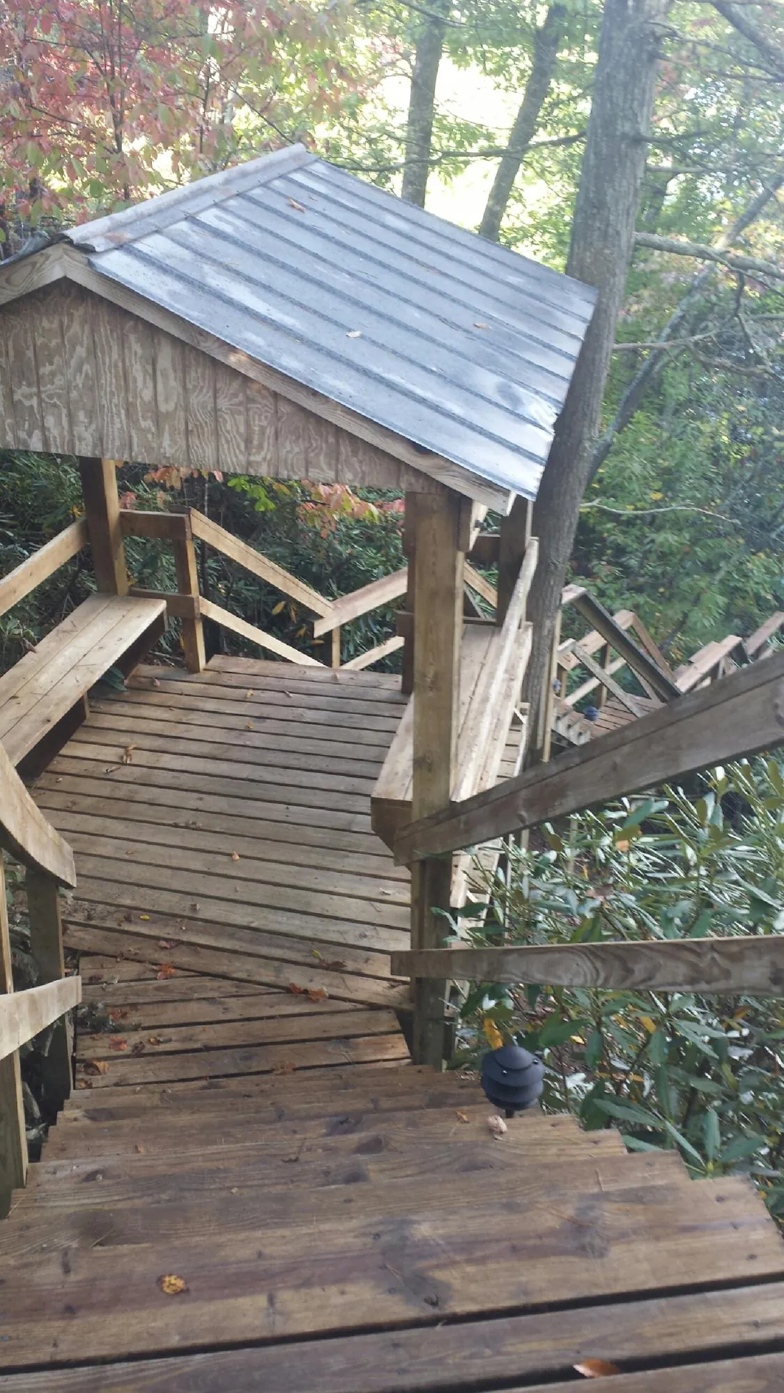Metal roofed shelter over wooden steps on a wooded walkway — Skylight Repair & Installation work by our crew in Huffman