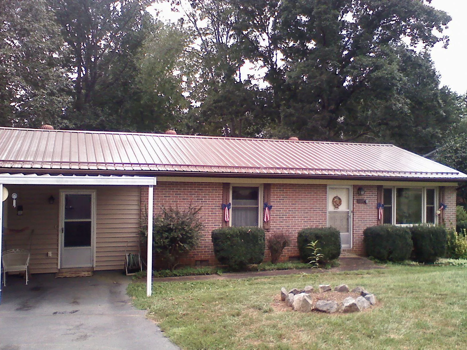 Bronze metal roof and carport on a brick ranch home — Roof Repair work by our crew in Huffman