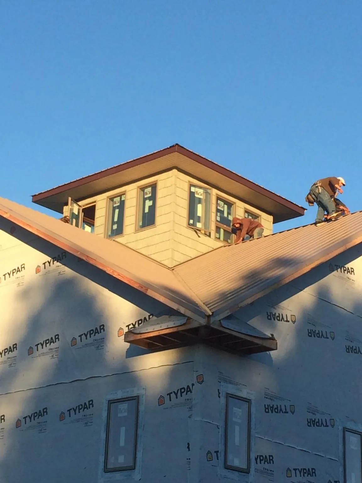 Roofers working around a rooftop cupola on a new metal roof at sunset — Roof Waterproofing in Huffman by Roofing Brothers